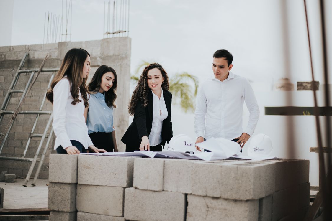 Profesionales coordinando un proyecto mediante la revisión de planos